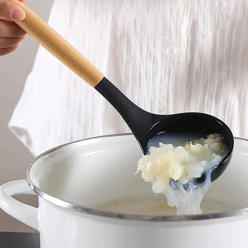 Silicone ladle with wooden handle scooping food from pot, part of a 12-piece kitchen utensil set.