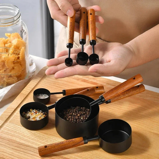 8-piece stainless steel measuring cup set with wooden handles for baking and bartending.