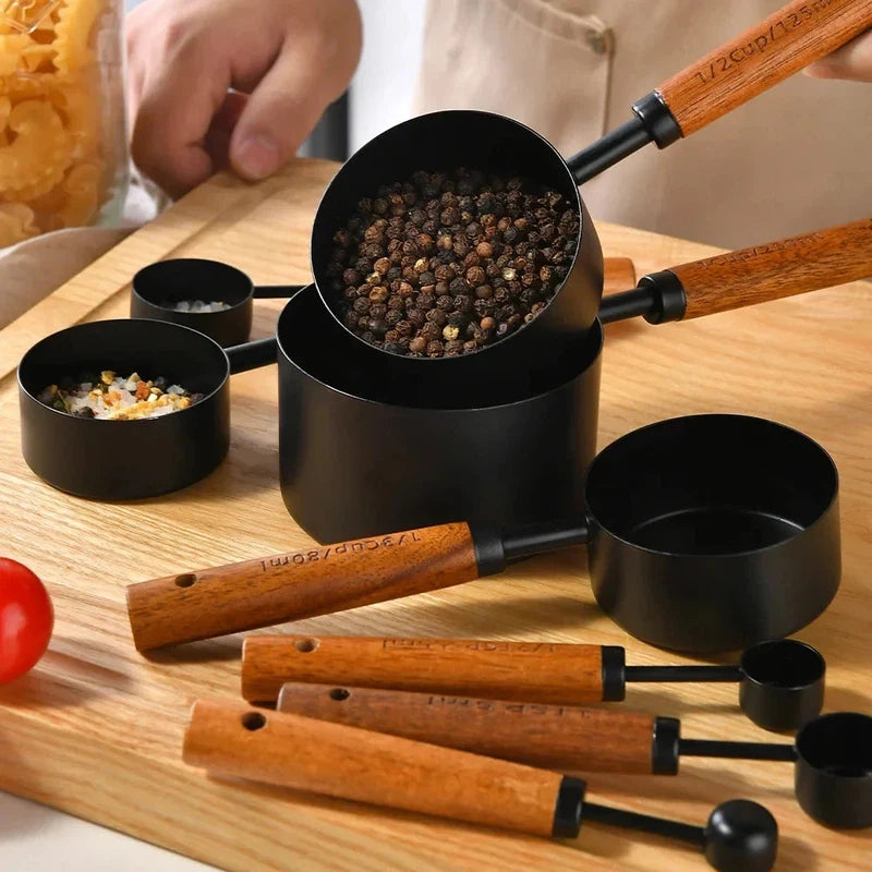 8-piece stainless steel measuring cups and spoons set with wooden handles for baking and bartending, displayed with spices.